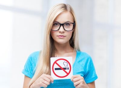djevojka koja na ulazu drži znak zabrane pušenja